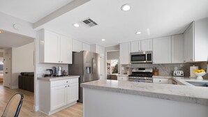 A modern kitchen with white cabinets, stainless steel appliances, and a marble countertop. - Lush Chic Living Private Backyard Heated Saltwater Pool (Indio)