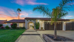 A residential house with a tiled roof, a driveway, and a well-maintained lawn. - Lush Chic Living Private Backyard Heated Saltwater Pool (Indio)
