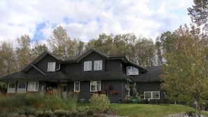 A two-story house with a dark exterior, multiple windows, and a well-maintained lawn.