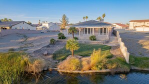 A residential area with houses, a small pond, and a grassy area with palm trees. - Well-appointed home just steps from the Colorado river! (Needles)