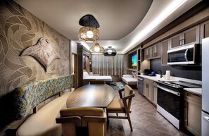 Eine moderne Küche mit Essbereich, ausgestattet mit einem großen Holztisch und Stühlen, einer eingebauten Mikrowelle und einer Sitzecke mit einer gemusterten Bank.
