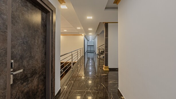 A modern hotel hallway with a marble floor, a staircase, and a door with a dark finish. - Treebo Siri Ambari Resorts (Piriyapatna)