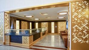 A lobby with a reception desk, a seating area, and decorative panels. - Treebo Siri Ambari Resorts (Piriyapatna)