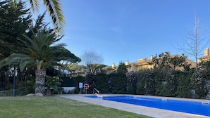 A swimming pool surrounded by a well-maintained lawn and palm trees. - Apartamento Para Parejas Reformado con Piscina y Wifi (Palafrugell)