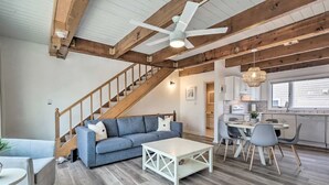 A spacious living area with a staircase, a dining table with chairs, and a kitchen area with a window. - Bethany Townhome-50ft to Shore! (Bethany Beach)