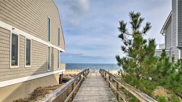 A wooden boardwalk leading to a beach, flanked by buildings with a view of the ocean. - Bethany Townhome-50ft to Shore! (Bethany Beach)