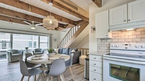 A modern kitchen with white cabinets, a built-in oven, and a dining area with a round table and chairs. - Bethany Townhome-50ft to Shore! (Bethany Beach)