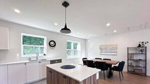 Eine moderne Küche mit weißen Schränken, einer Holztischinsel und einem Essbereich mit Tisch und Stühlen.