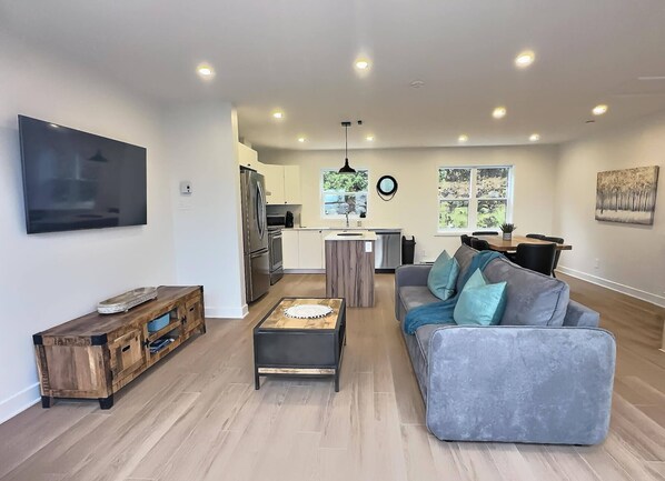 A modern living room with a grey sofa, wooden coffee table, and a TV mounted on the wall. - Condo à Mont-blanc Près des Pistes (Mont-Blanc)