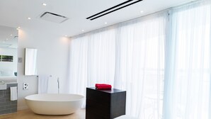 Ein modernes Badezimmer mit freistehender Badewanne, einem schwarzen Waschtisch und einem großen Spiegel.