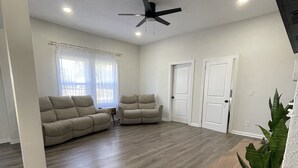 A spacious living room with a large sectional sofa, a ceiling fan, and a wooden coffee table. - Modern Home in Gallatin  (Gallatin)