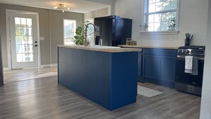 A modern kitchen with a central island, dark blue cabinets, and a stainless steel oven. - Modern Home in Gallatin  (Gallatin)