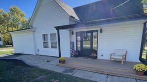 A white building with a black roof, a welcome sign, and a bench outside. - Modern Home in Gallatin  (Gallatin)