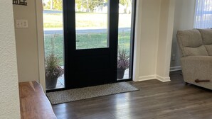 A modern living room with a dark door, a bench, a sofa, and a ceiling light fixture. - Modern Home in Gallatin  (Gallatin)