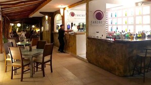 Ein Restaurant mit Holzbalken, Tischen, Stühlen, einer Bar und einer Theke mit Speisekarte.