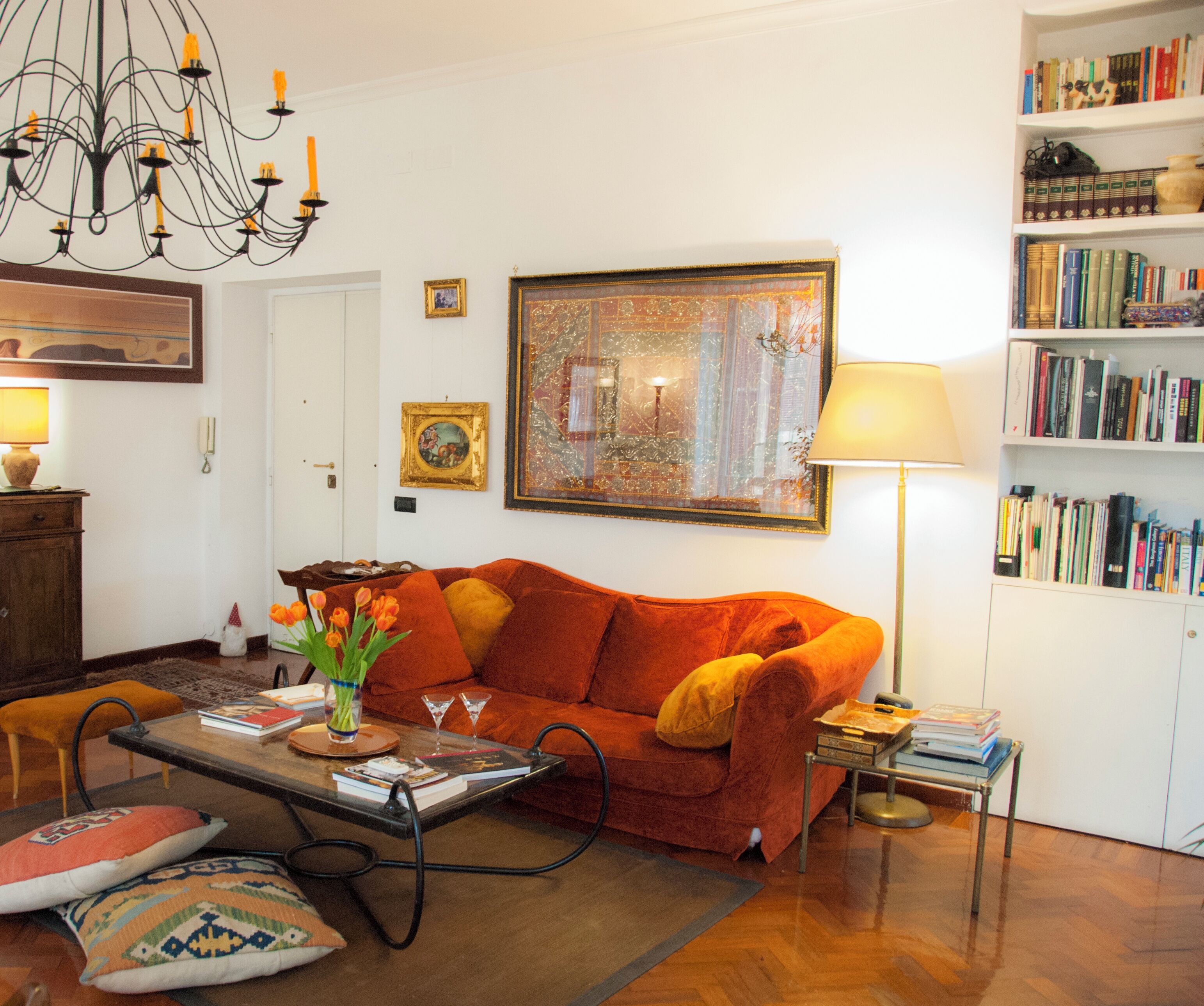 A living room with a sofa, a coffee table, a bookshelf, and a chandelier.