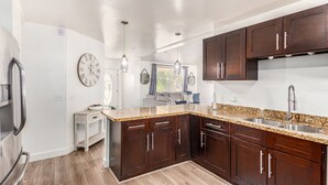 A modern kitchen with dark wooden cabinets, a granite countertop, and stainless steel appliances. - Serenity in the heart of Phoenix's Camelback East/Biltmore 3 bedrooms 2 baths  (Phoenix)