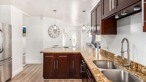 A modern kitchen with dark wood cabinets, granite countertops, stainless steel appliances, and a large clock on the wall. - Serenity in the heart of Phoenix's Camelback East/Biltmore 3 bedrooms 2 baths  (Phoenix)