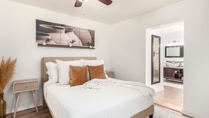 A bedroom with a bed, a ceiling fan, a nightstand, a vase with dried plants, and a painting on the wall. - Serenity in the heart of Phoenix's Camelback East/Biltmore 3 bedrooms 2 baths  (Phoenix)