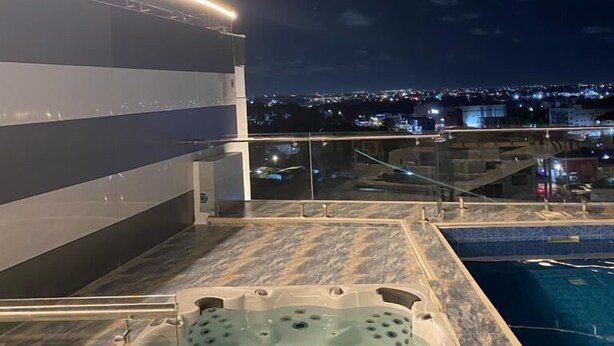 Zona de piscina en la azotea con jacuzzi y vista nocturna de la ciudad.