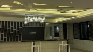 Un hall amplio con una lámpara moderna, suelos de mármol y un mostrador de recepción.