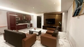 Una sala de estar moderna con un juego de sofá, una mesa de centro y un televisor montado en una pared de madera.