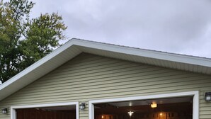 A two-car garage with a gravel driveway and a wooden fence.