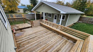A wooden deck with a bench, a small shed, and a fenced yard.