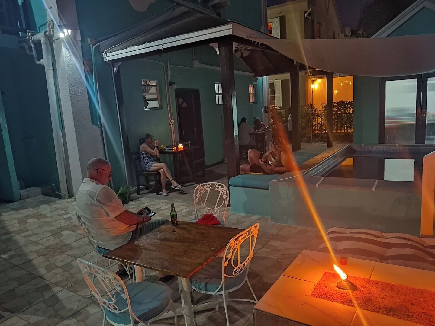 An outdoor seating area with tables and chairs, a covered section, and a view of the sea.