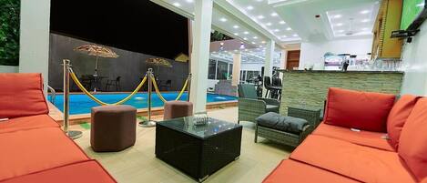 Un espace piscine intérieure avec des sièges et un bar.