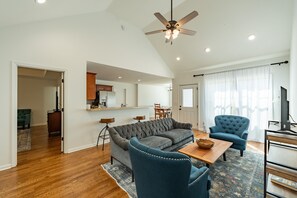 A modern living room with a sectional sofa, a blue armchair, and a coffee table. - Charming Cottage located 15 minutes from Columbia, TN (Culleoka)