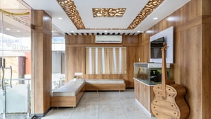 A modern room with a wooden bench, a fish tank, and a mounted TV. - Treebo Four Seasons, Near Mysore Palace (Mysore)