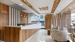 A hotel reception area with a wooden reception desk, a seating area with a sofa, and a decorative ceiling. - Treebo Four Seasons, Near Mysore Palace (Mysore)