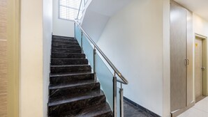 A staircase with dark marble steps and a metal handrail, leading to a door with a wooden finish. - Treebo Four Seasons, Near Mysore Palace (Mysore)