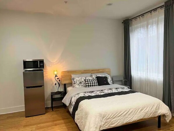 Cozy retreat with a comfortable bed, refrigerator, and large window.