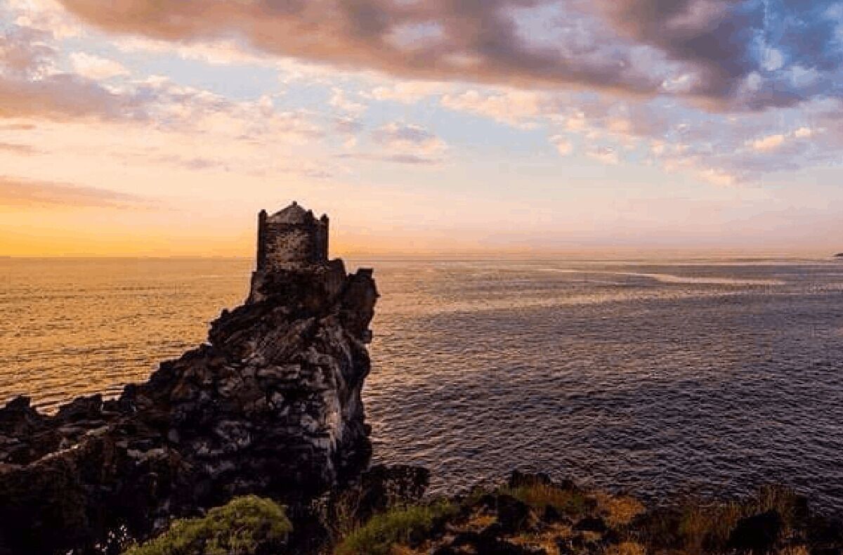 A coastal landscape with a historic stone tower overlooking the sea.