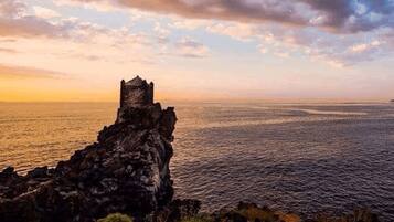 A coastal landscape with a historic stone tower overlooking the sea.