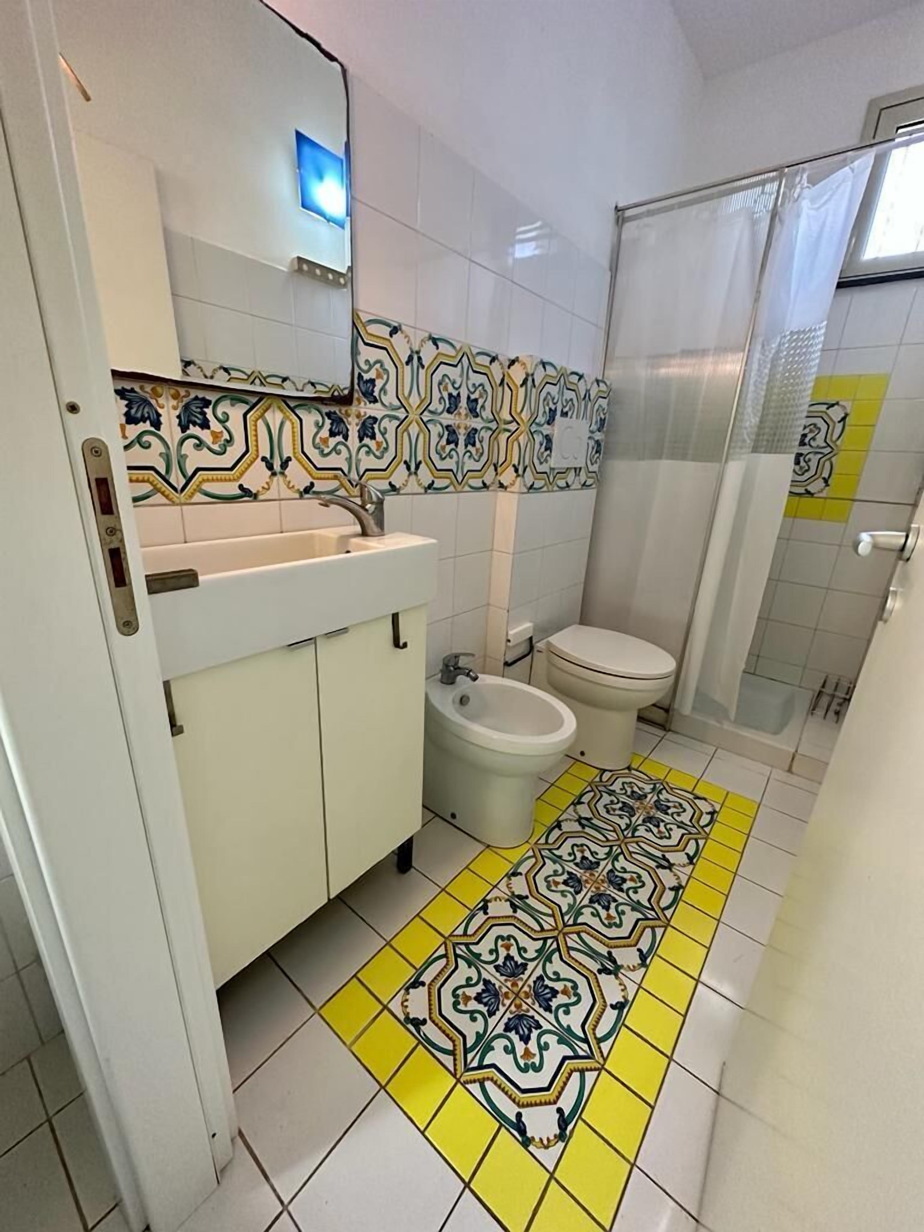 Une salle de bain avec un lavabo blanc, un bidet, des toilettes et un espace douche.