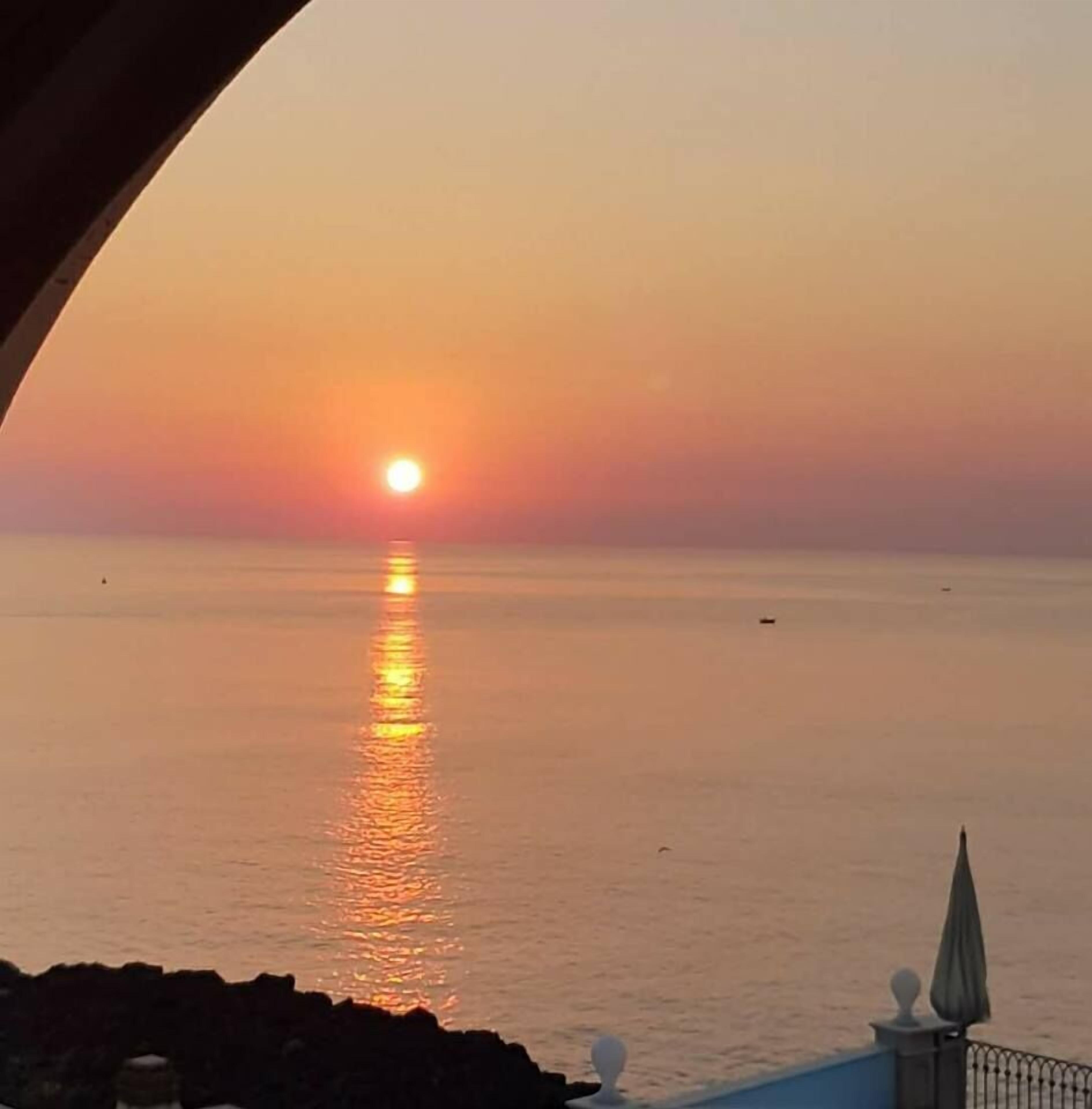 A sunset over a calm sea with a clear horizon.