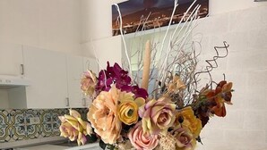 A kitchen with white cabinets, a tiled backsplash, and a vase of flowers on the counter.