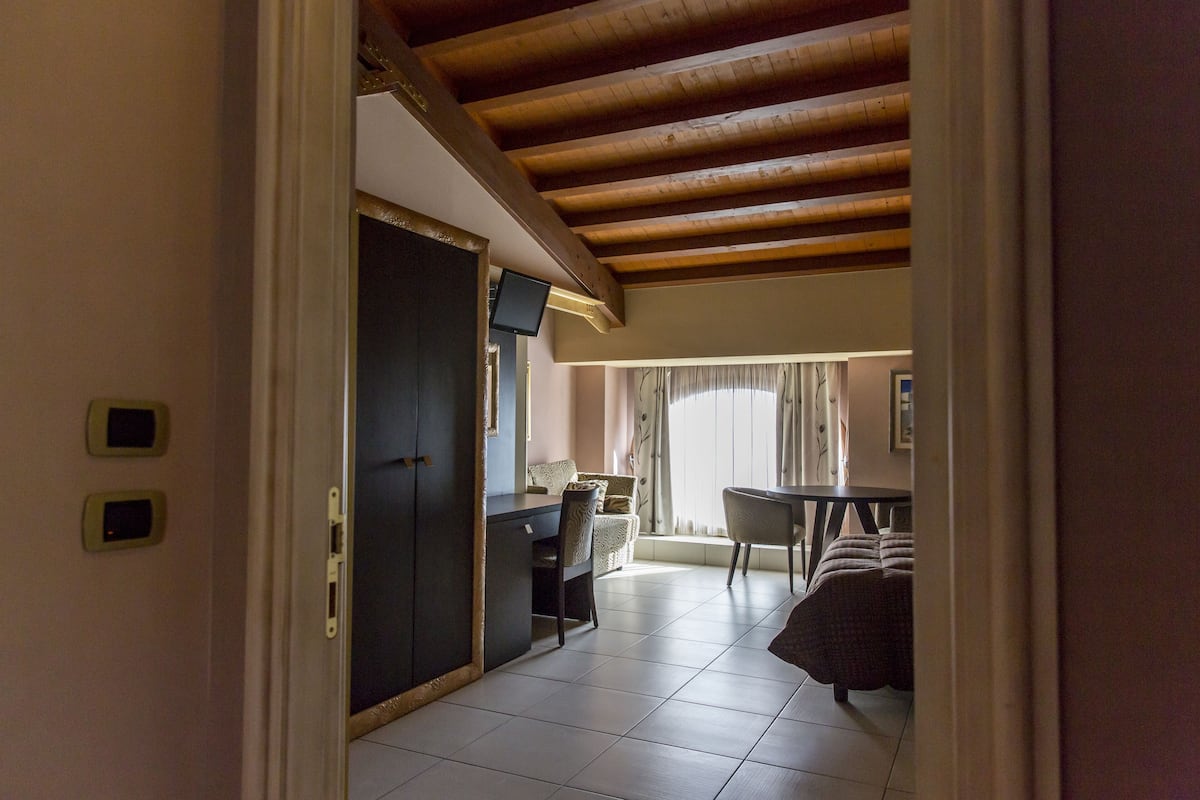 A room with a wooden ceiling, a dining area with a table and chairs, and a sofa.