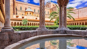 A courtyard with a fountain, columns, and a building with arches and a dome.