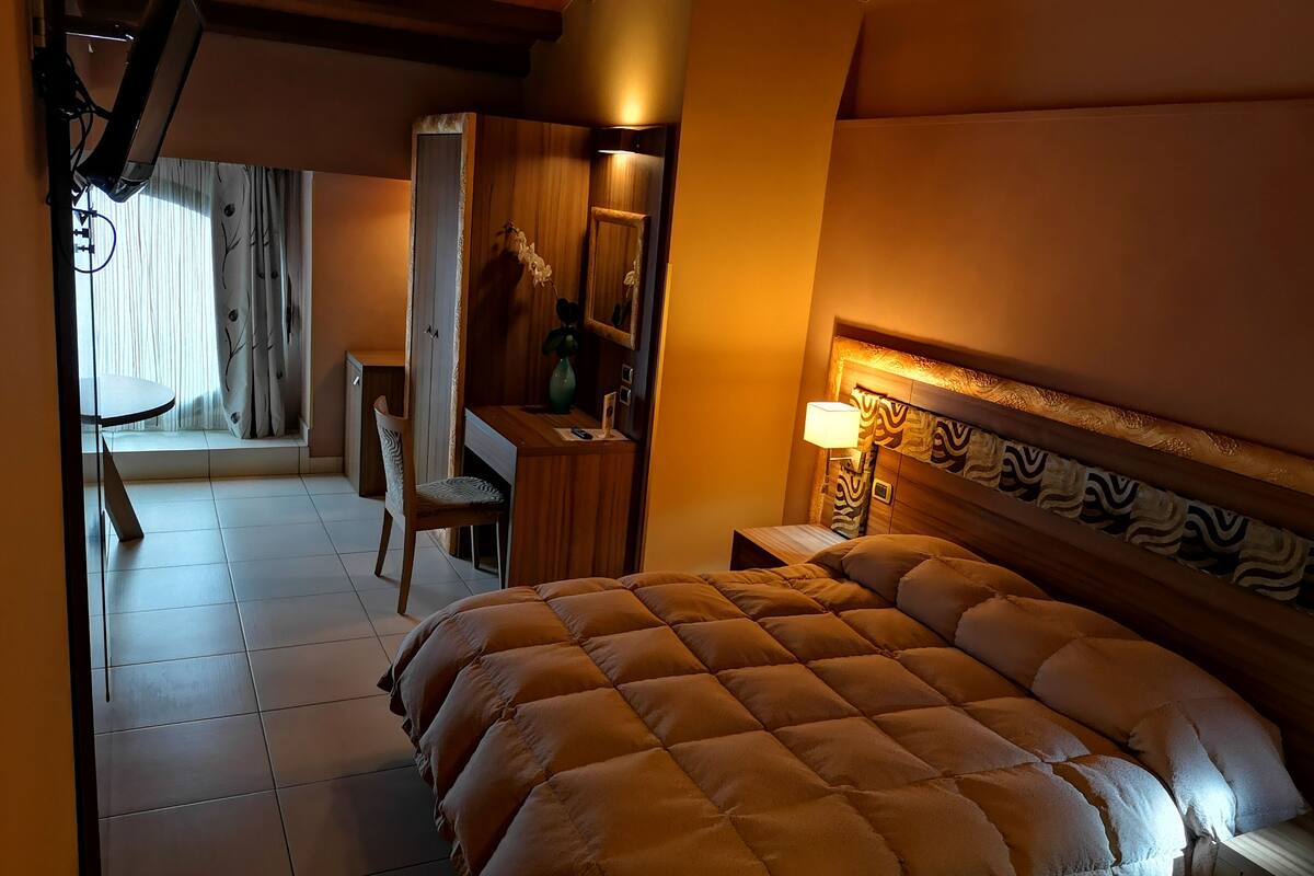 A hotel room with a bed, a desk, a chair, and a small table.
