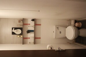 A bathroom with a toilet, sink, and mirror.