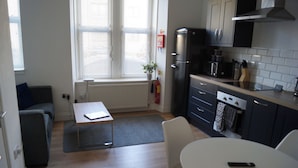 A compact kitchen with a dining area, a sofa, and a radiator. - Luxury Apartment - Central Dundee - Pet Friendly (Dundee)