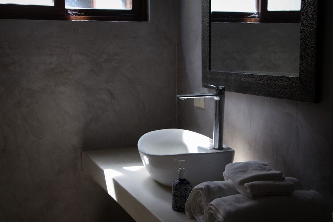Un baño moderno con un lavamanos grande de color blanco, un espejo y un perchero para toallas.
