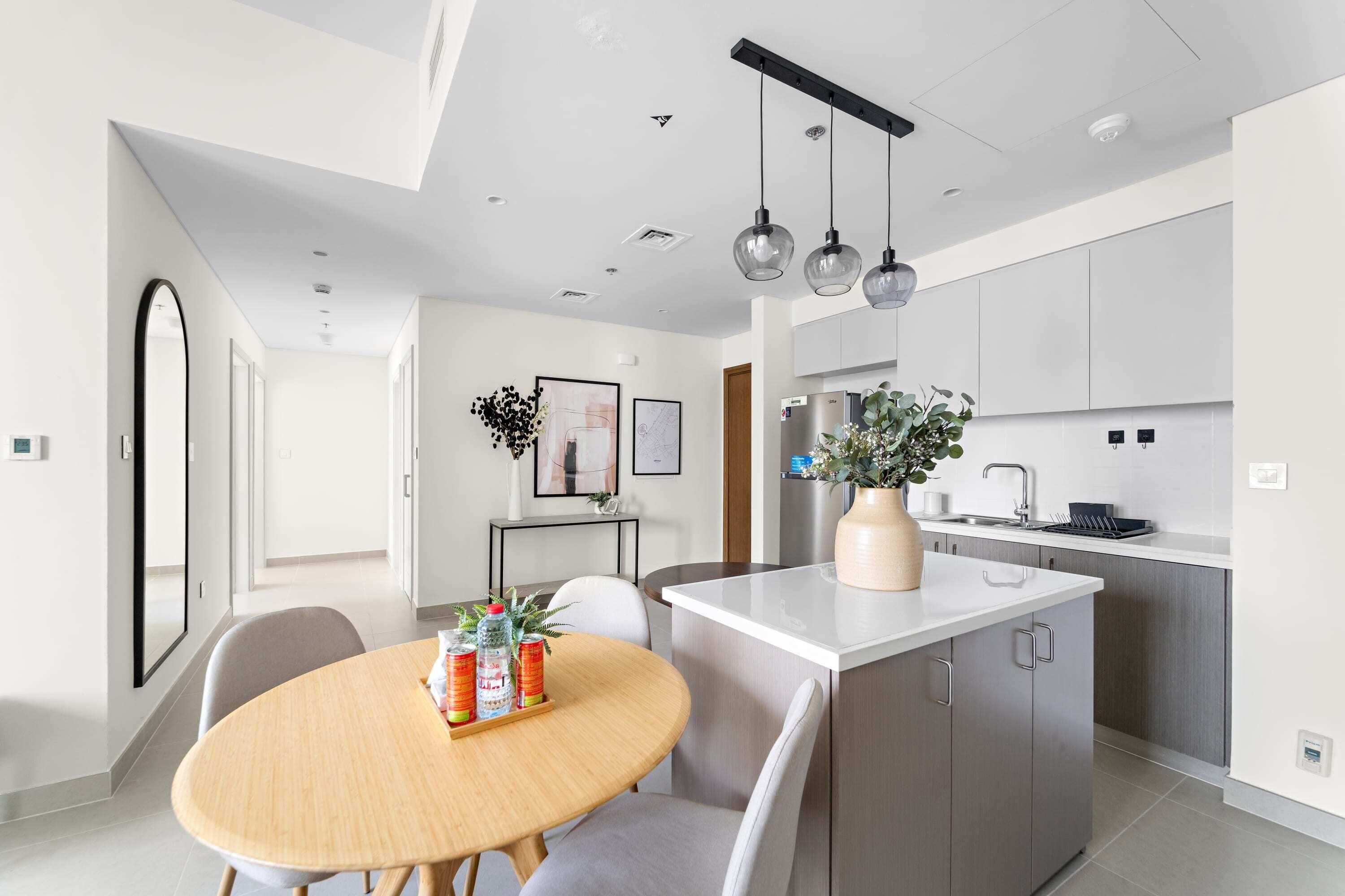 A modern kitchen with a central island, stainless steel appliances, and pendant lighting.