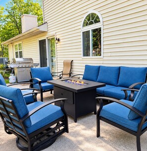 An outdoor seating area with a grill, chairs, and a table.
