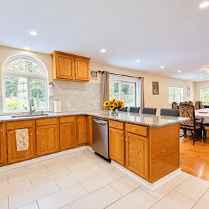 A kitchen with wooden cabinets, a built-in dishwasher, and a large island with a sink.