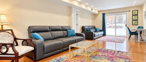 Una sala de estar moderna con un sofá, un sillón, una mesa de centro y una alfombra colorida.